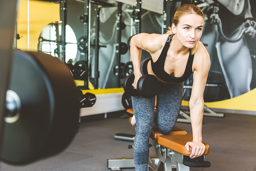 Working out with dumbbell weights at the gym. Heavy lifting women exercising are lifting dumbbells. Fitness muscular body.Workout at gym.